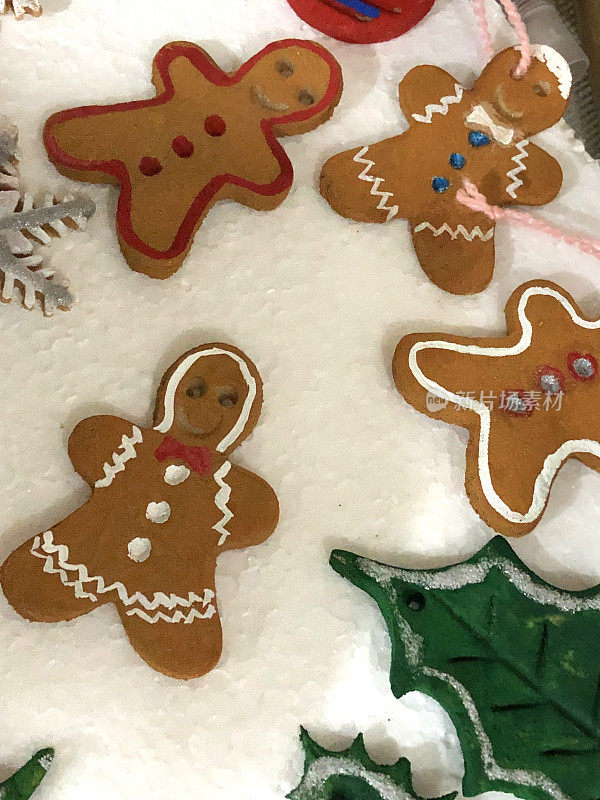 这是一个冬季圣诞手工制作环节，制作由树、冬青树叶、雪花、姜饼人、星星、小饰物和雪人组成的圣诞树装饰品，从饼干切割刀上切下来的烤盐面团饼干被用海报漆刷刷上