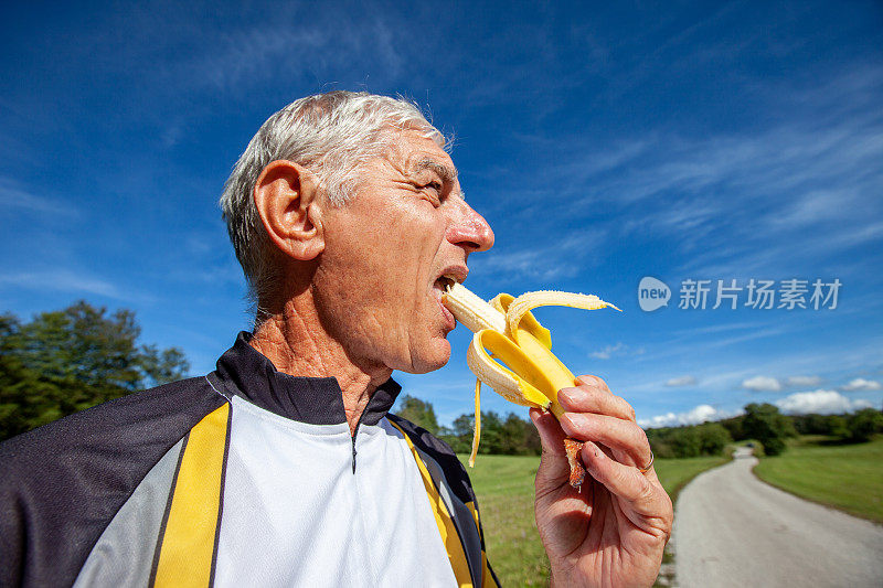骑自行车的老人在乡村路上吃香蕉