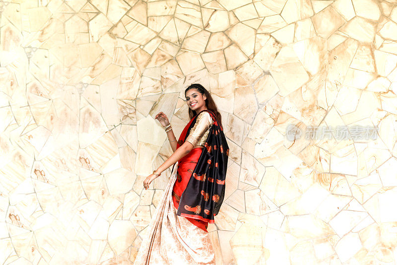 快乐年轻美丽的印度妇女在传统纱丽与黄金珠宝