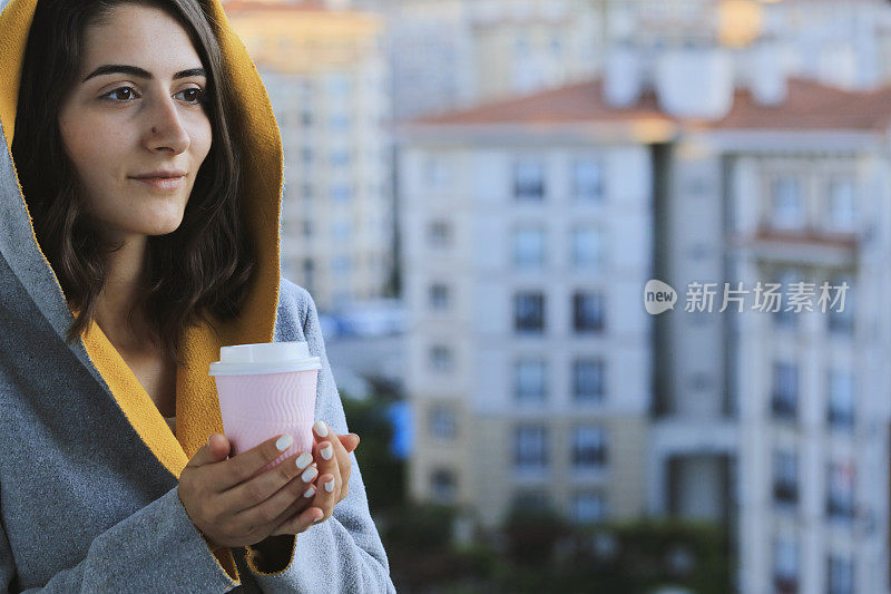 年轻女子拿着热咖啡和手机