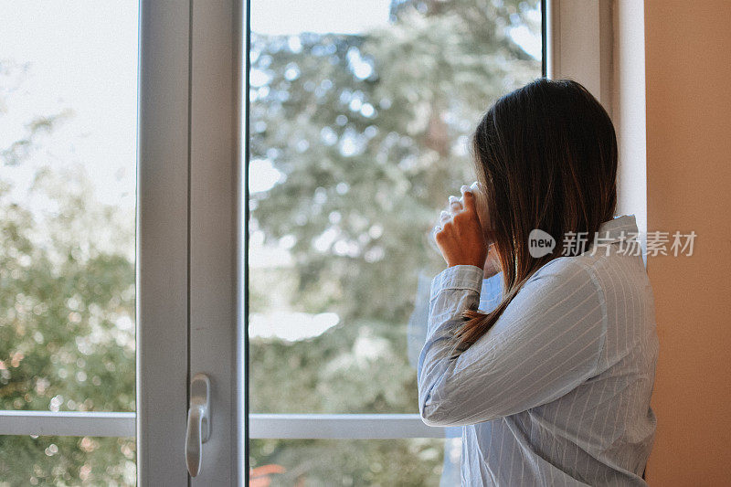 女人在窗边喝咖啡后醒来，阳光明媚的早晨。生活方式的概念