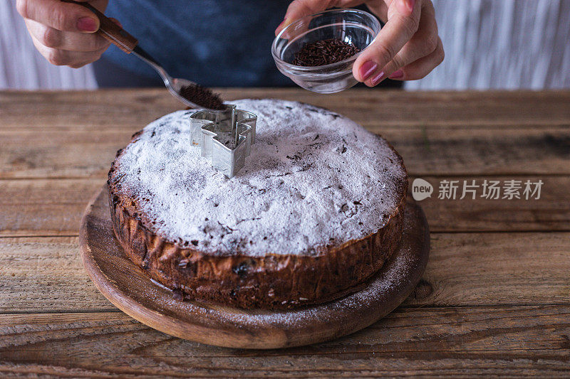 厨师用巧克力屑和松树形状的模具装饰新鲜制作的圣诞饼干