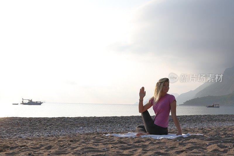 年轻女子在海滩上练习日出瑜伽