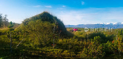 冰岛公路旅行:红色汽车停在路边附近的草皮屋