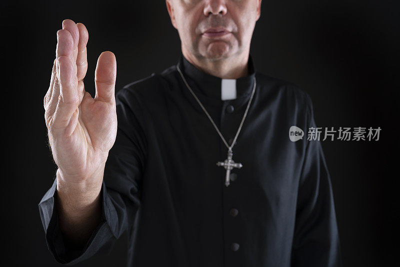 牧师祝福的手与袈裟在深黑色