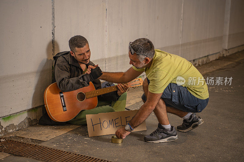 善良的人正在给街头吉他手捐款