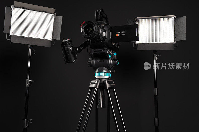 专业影院摄像机在一个摄像机三脚架和两个照明LED面板在黑色工作室背景