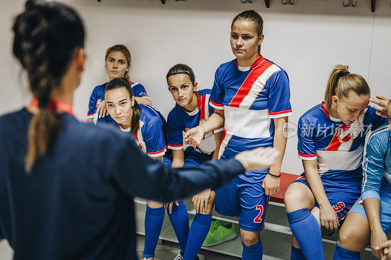 女足球运动员在更衣室里和她的教练说话。