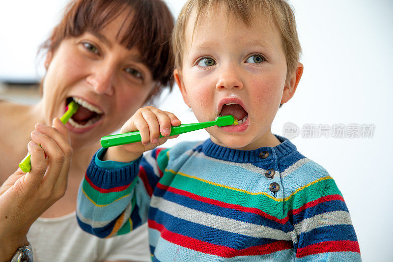 快乐的妈妈和小男孩学习正确地刷牙-库存照片