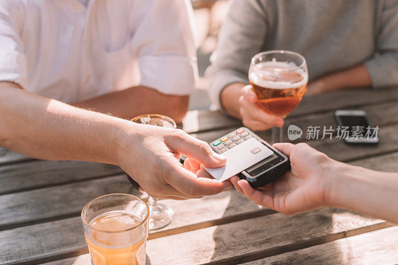 男性的手在餐厅用信用卡付款的特写-生活方式的照片，人们放松在啤酒厂和支付与塑料卡在桌子上