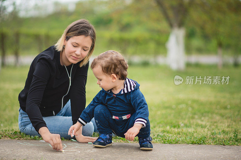 母亲在后院教孩子用粉笔画画