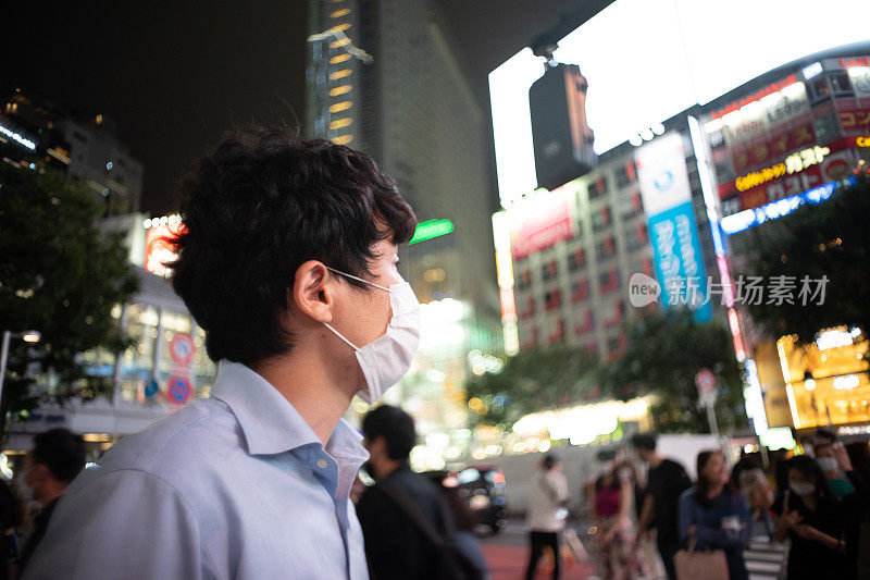 一幅戴着面具的亚洲男子的肖像，展示着城市的夜景