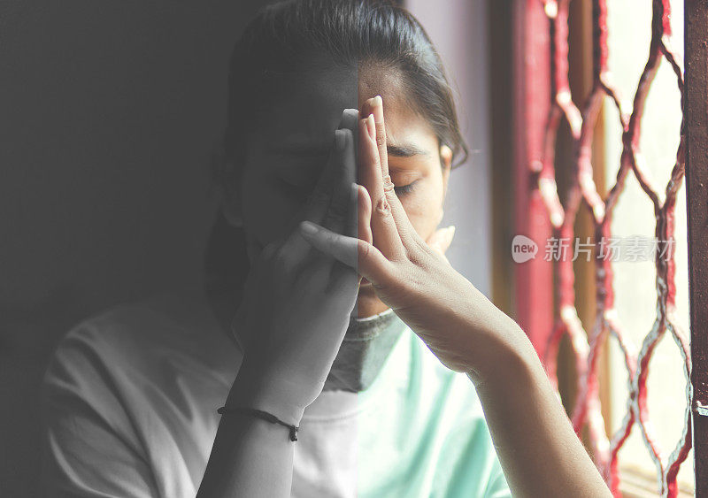 这个悲伤的女孩正在保护自己，戴着口罩，在家里自我隔离。