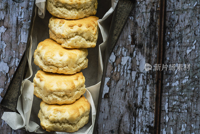 五个刚烤好的烤饼放在一个有油脂衬里的金属罐里