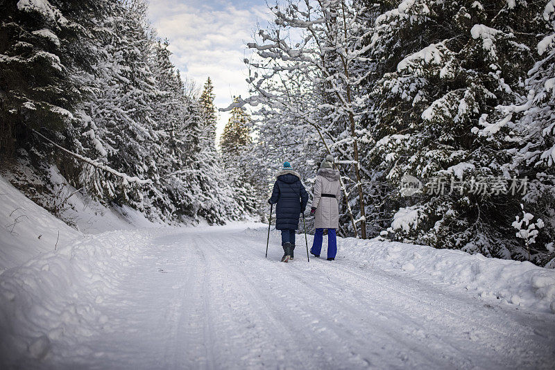 年长的女人和她的成年女儿一家喜欢在冬季森林徒步旅行。