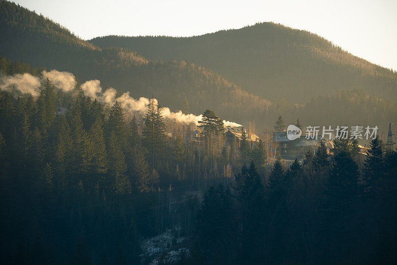 大雾清晨山间的舒适之家。山中的风景雾蒙蒙的。沐浴在阳光下的美妙早晨