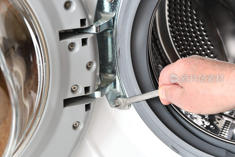 洗衣机的维修保养。工人用钥匙拧开洗衣机的门。