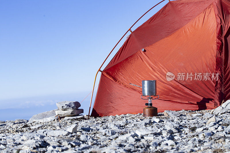 在徒步旅行期间的帐篷背景上，带有现代钛锅的燃气弹野营喷气炉