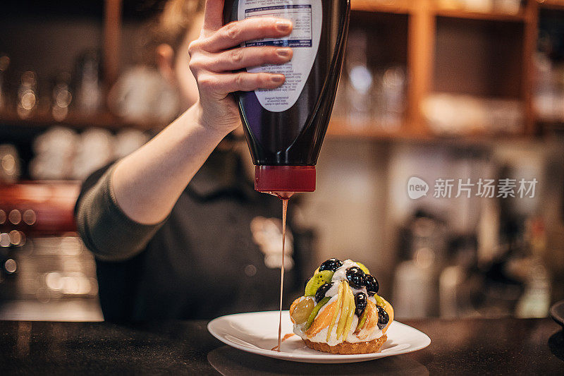 女糖果师在水果蛋糕上浇甜品