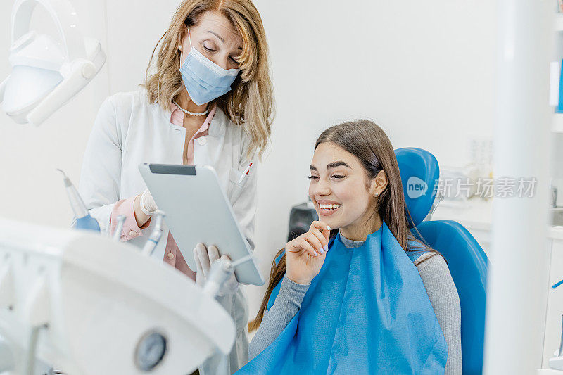 牙医给病人看牙科治疗的结果。牙医戴着防护口罩