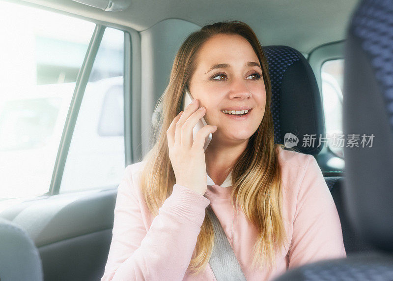 快乐的女人看起来很高兴她在车里听到她的手机