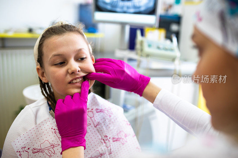 一位女牙医在检查一个可爱的年轻女孩的牙齿