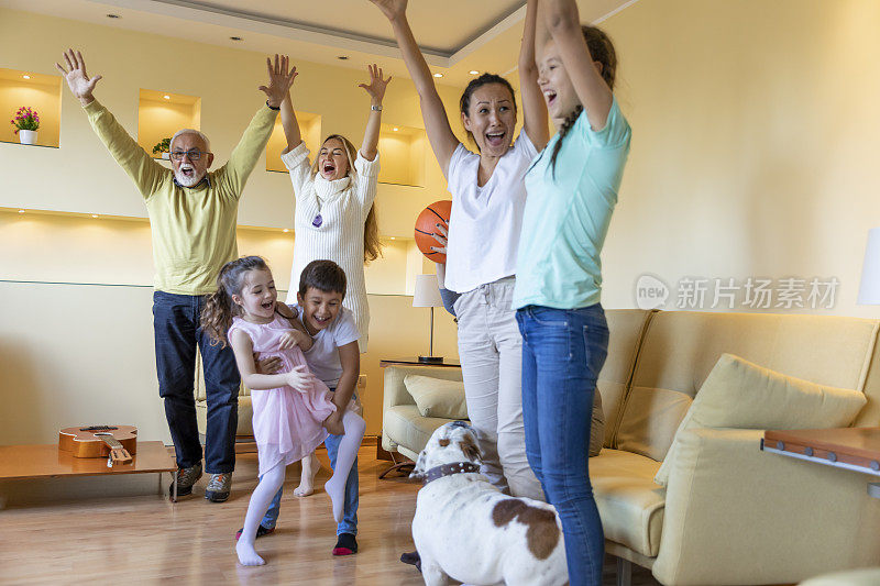 一个欢呼的家庭正在一起看电视上的篮球比赛。