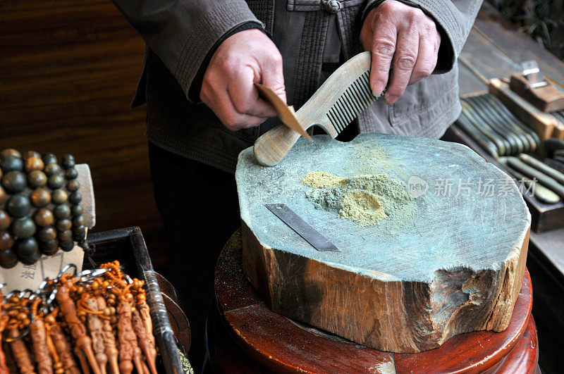一位老艺术家正在制作一把木梳子在中国市场上出售。