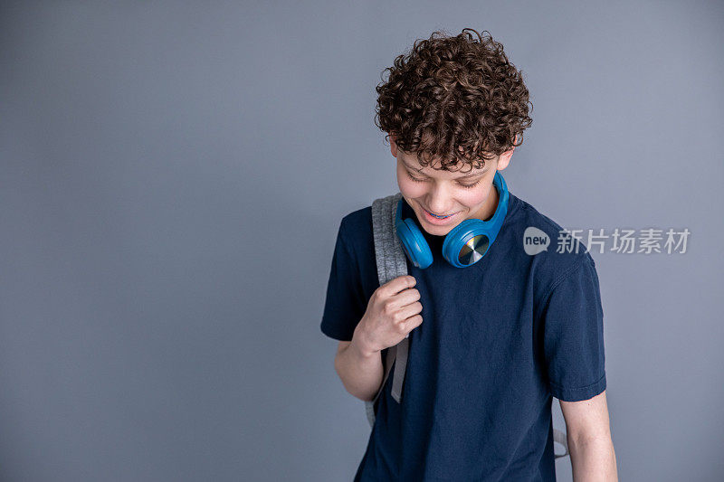 十几岁的男孩是学生，背着背包，戴着耳机