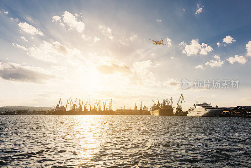 集装箱货轮和货机的物流运输与工作吊桥在港口的黄昏天空