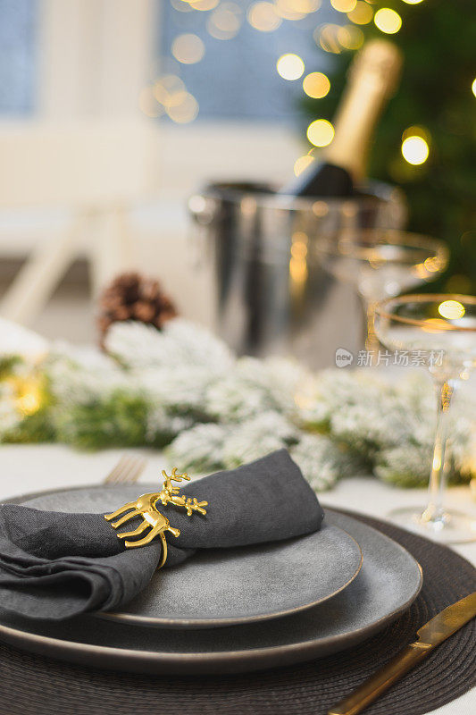 圣诞节日餐桌摆设，金色装饰，香槟。家庭节日晚餐或新年聚会。