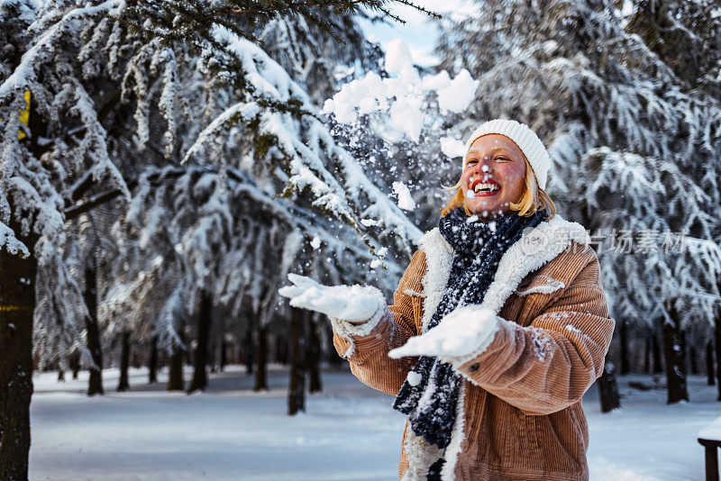 穿着冬衣的女人在森林里扔雪