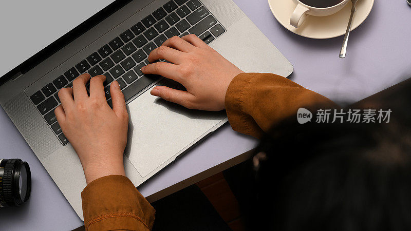 女性工作时使用笔记本电脑，敲击键盘