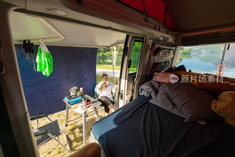 坐在露营车旁的椅子上喝咖啡的女人