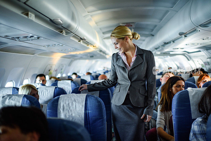 快乐的空姐在飞机上与乘客交谈。