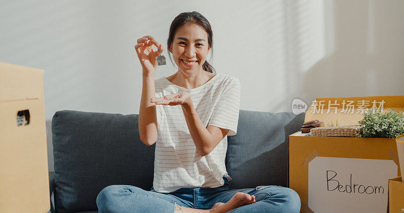 年轻的亚洲女人秀赞美房子的钥匙搬到第一个自己的新房子。