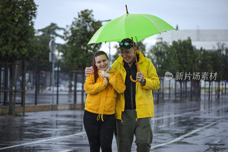 几代同堂的家庭在雨中在城市里散步