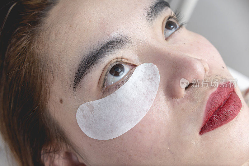 一位亚洲妇女，眼垫放在她的下睫毛下面。准备睫毛延长程序。