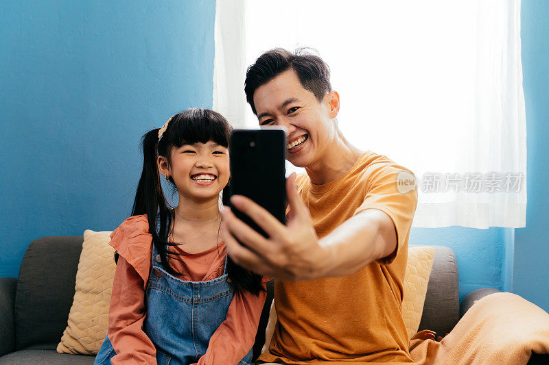 亚洲家庭的父亲和女儿在家里用手机自拍