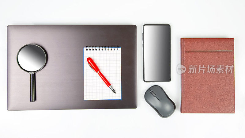笔记本电脑，放大镜，电脑鼠标，智能手机，笔，白底记事本。商业项目和在线购买商品