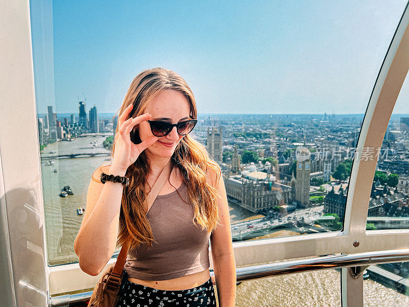 可爱的偷拍肖像一个快乐的年轻女子站在摩天轮与伦敦的观点，英国