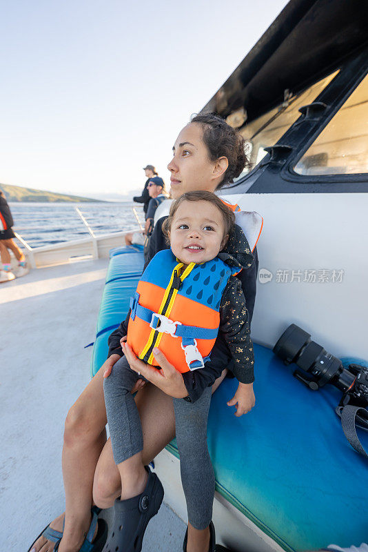 妈妈和蹒跚学步的女儿在船上享受观鲸之旅