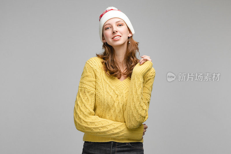 圣诞妇女肖像的女孩戴着圣诞老人的帽子，人手势的相机和显示的情绪。工作室概念与人在灰色背景和复制空间。新年摄影