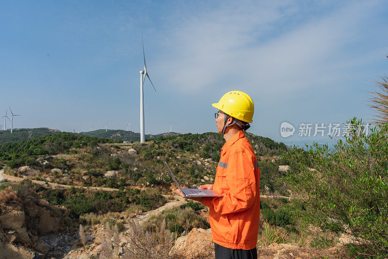 工程师在风力发电场使用笔记本电脑