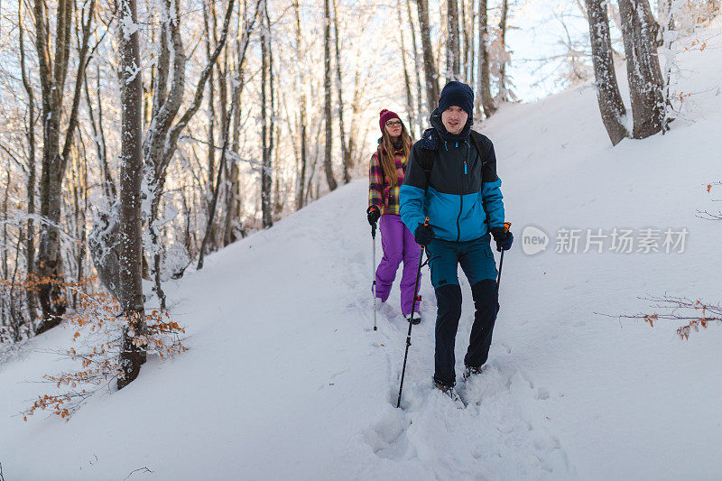 年轻的男性徒步旅行者和他的女性朋友一起从雪山小径上爬下来