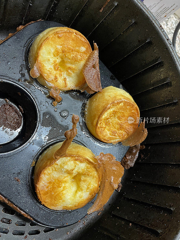 个人约克郡布丁在不粘锅松饼烤盘在空气炸锅烹饪的特写图像，高度视图