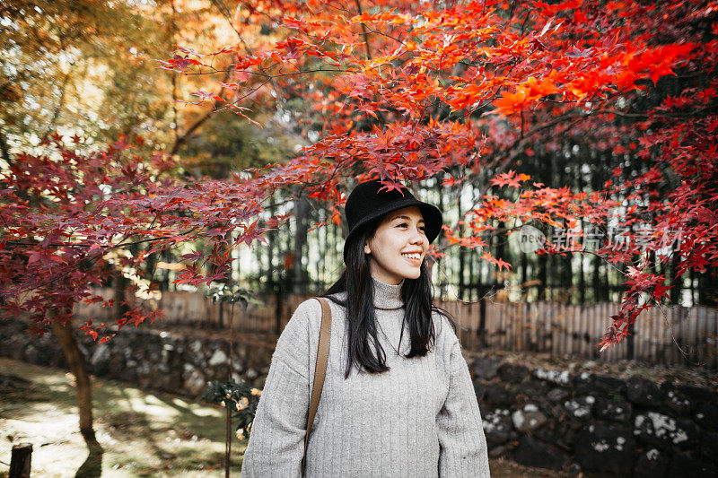 一位年轻的亚洲妇女正在乡村欣赏美丽的秋景。