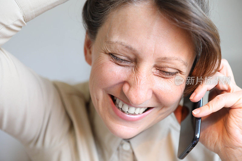 漂亮的中年女人手里拿着智能手机。