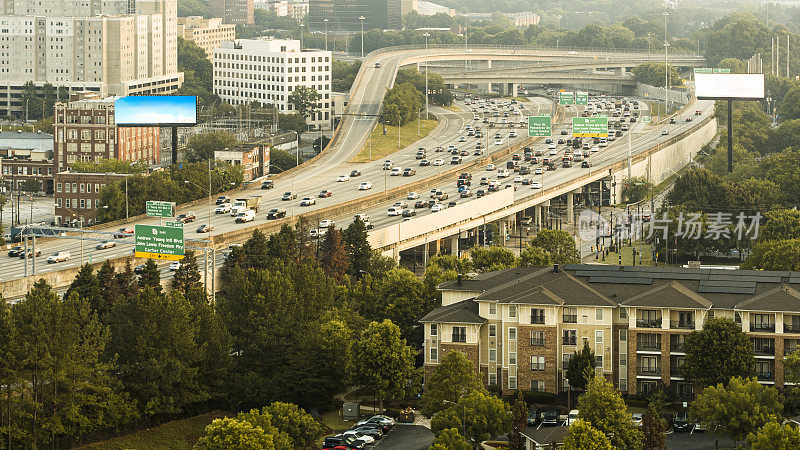 佐治亚州亚特兰大市中心附近蜿蜒的高速公路上交通拥挤。独立的住宅与远处的高层建筑形成对比。鸟瞰图