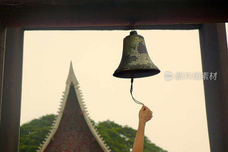 年轻女子在寺庙里摇佛钟